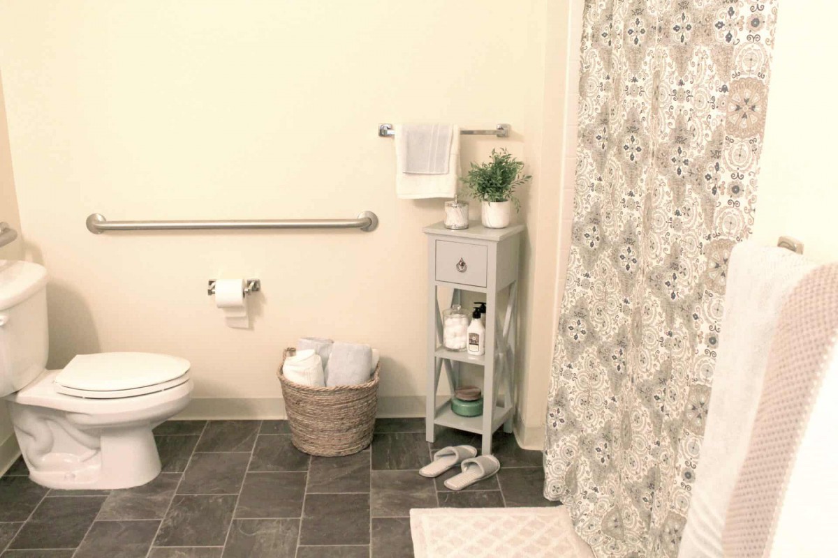 A neatly organized bathroom with a decorative shower curtain and small storage shelf.