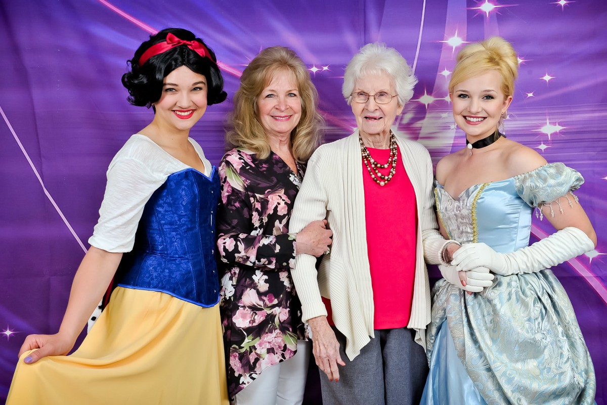 A group photo featuring two people in princess costumes alongside family members.