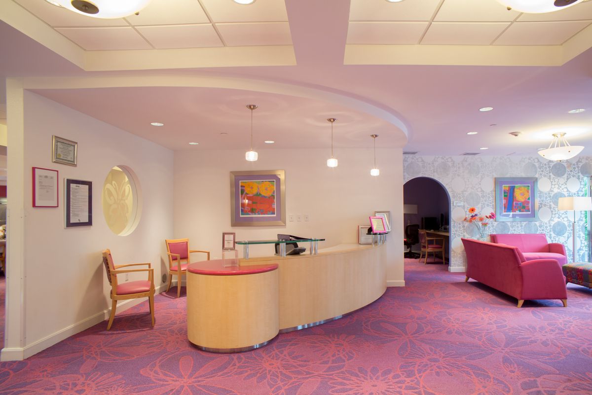 A modern reception area with curved desk and vibrant carpet.