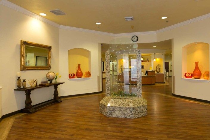 A warmly decorated lobby area with a central fountain and art pieces on the walls.