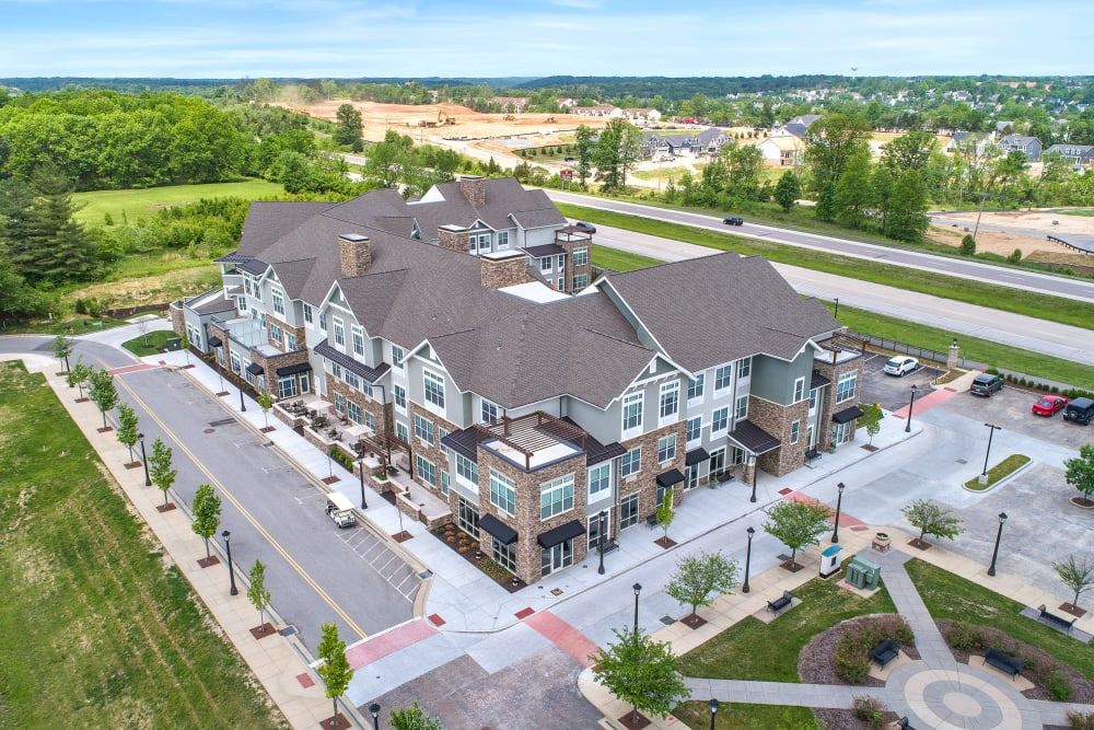 Aerial view of a mixed-use development with commercial and residential spaces surrounded by roads and greenery.
