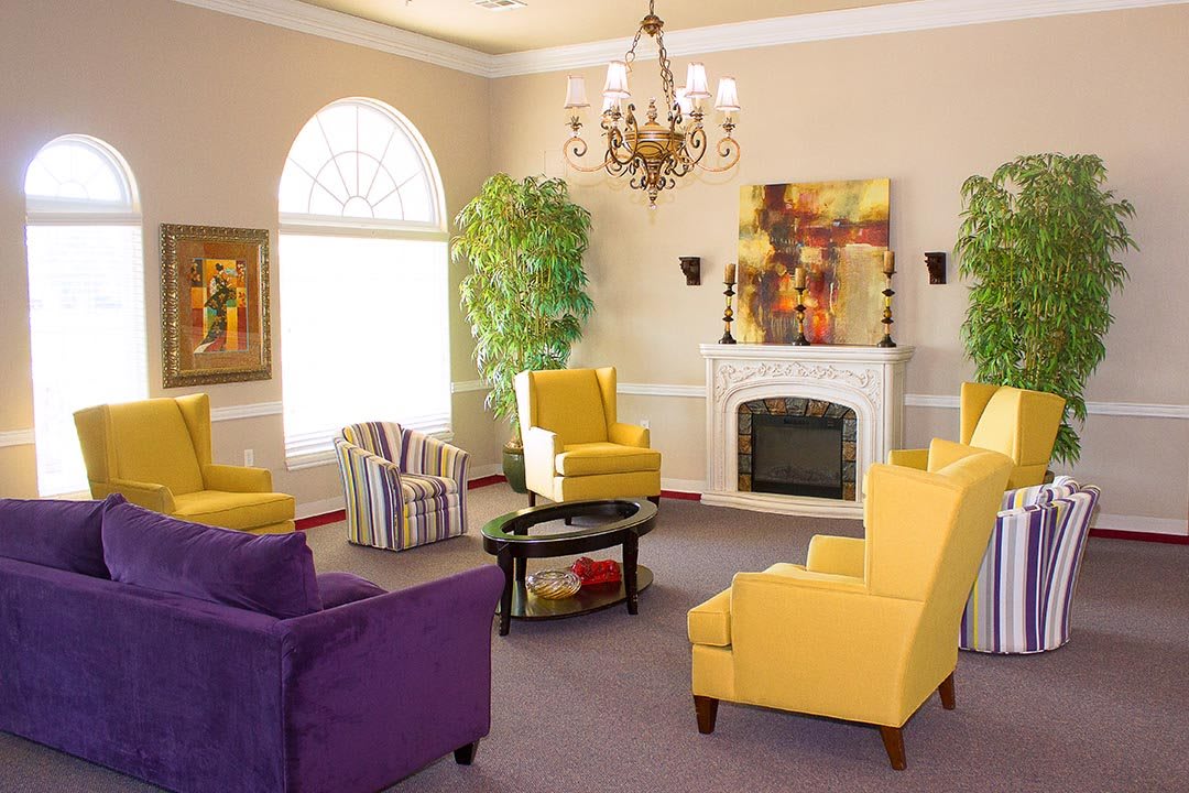 A vibrant and cozy living room featuring a mix of yellow and purple chairs, a fireplace, and elegant decor.