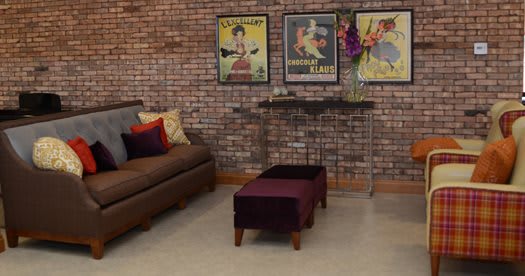 A stylish living room with a brick wall, adorned with vintage posters and modern furniture.