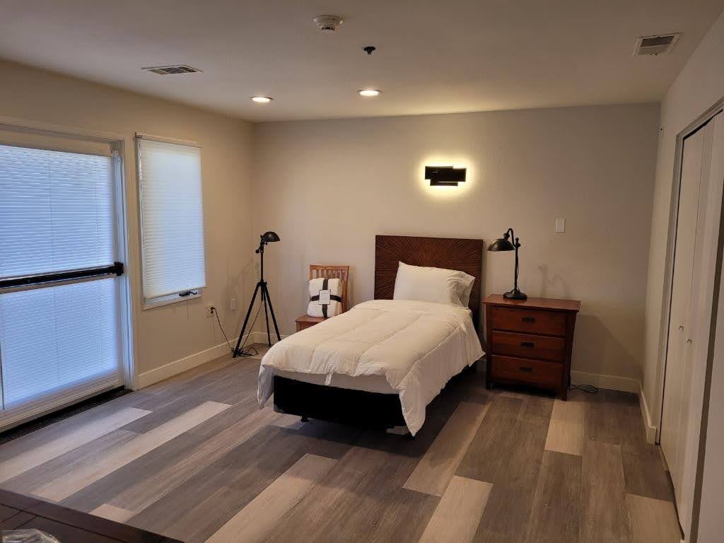 A modern, minimalist bedroom with a single bed and wooden flooring.