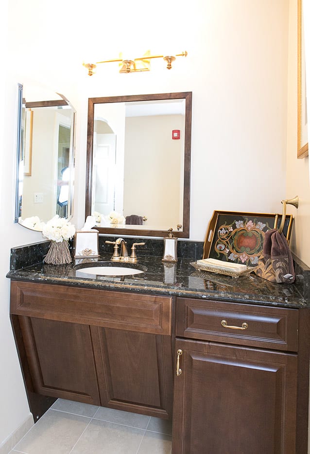 A neatly arranged bathroom with a dark countertop, sink, and decorative elements.