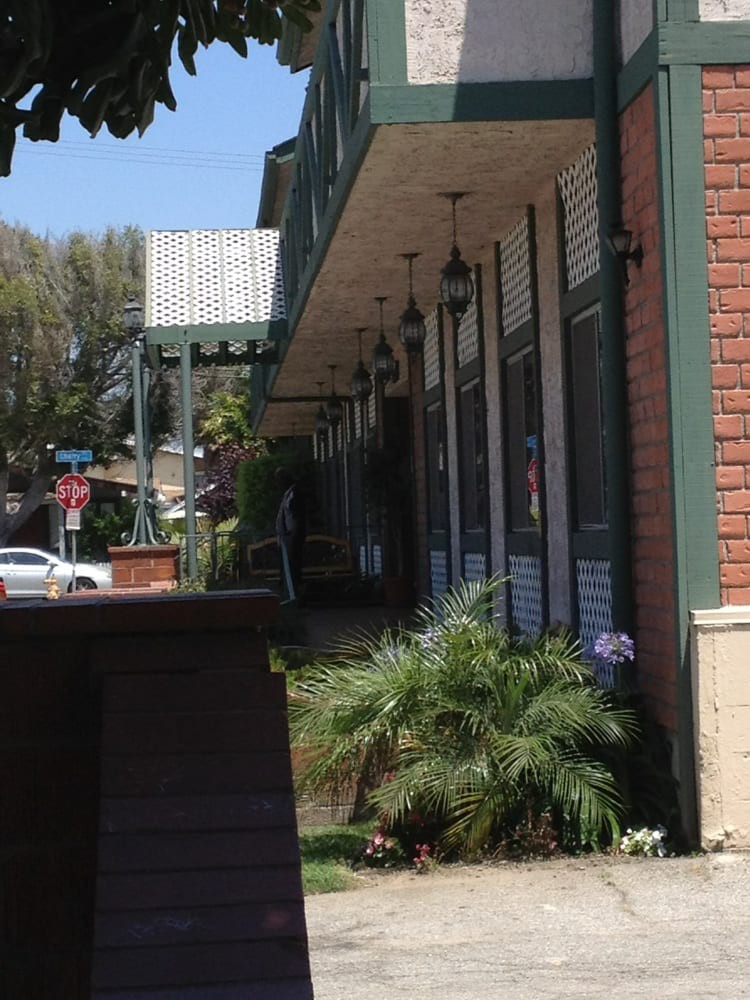 A street view of a building with plants and outdoor lights on a sunny day.