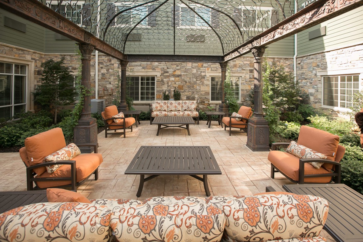 An elegant outdoor patio featuring cushioned seating under a pergola.