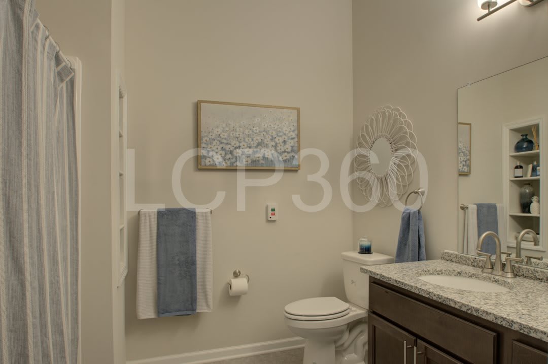 A neatly organized bathroom featuring a sink, toilet, and decorative elements like towels and wall art.