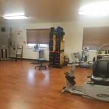 A spacious fitness room equipped with various exercise machines and weights.