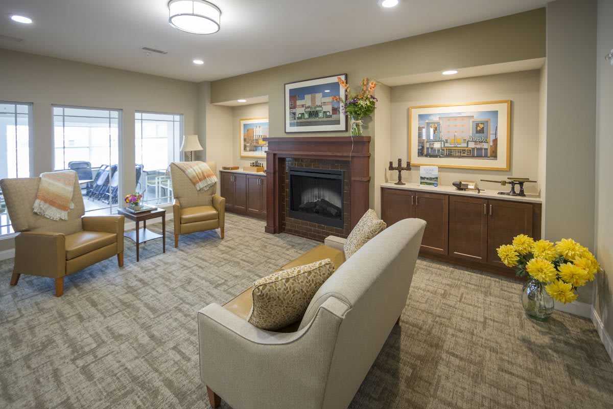 A cozy living room with a sofa facing a fireplace, complemented by elegant artwork and warm lighting.