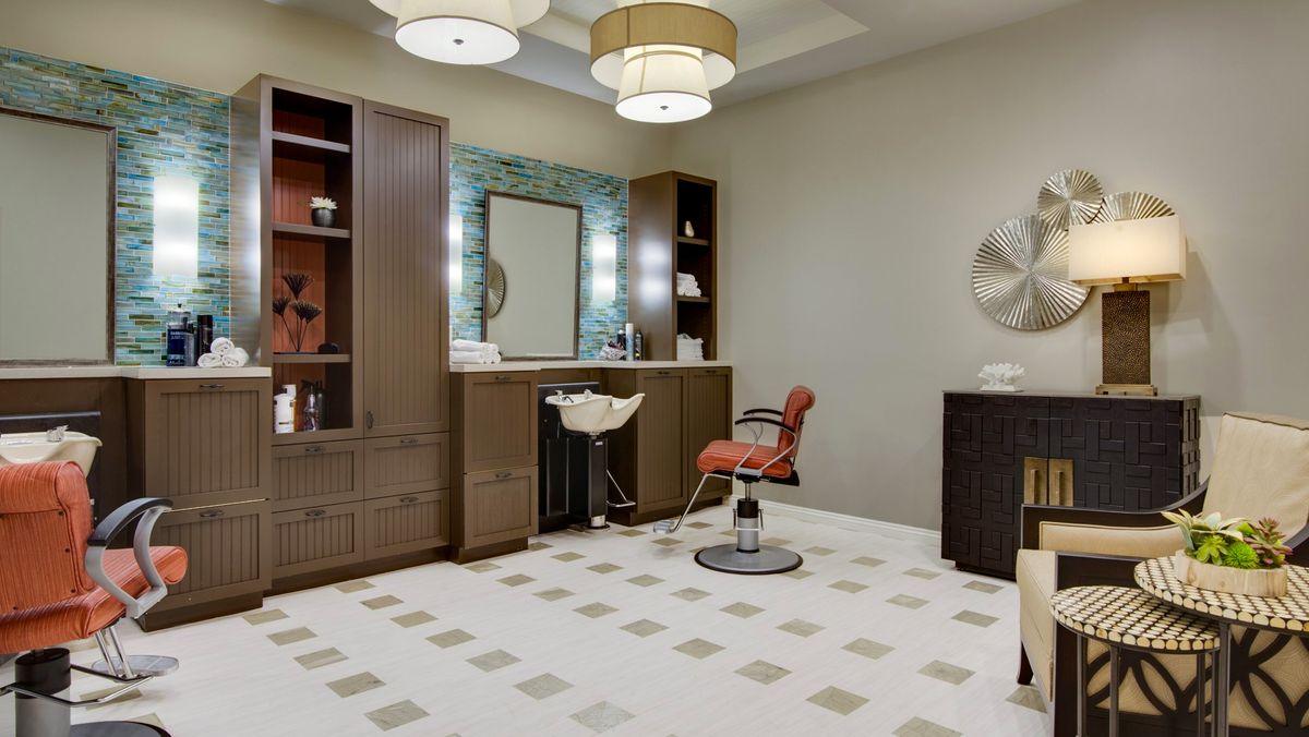 A modern hair salon interior with stylish furniture, soft lighting, and a large mirror.