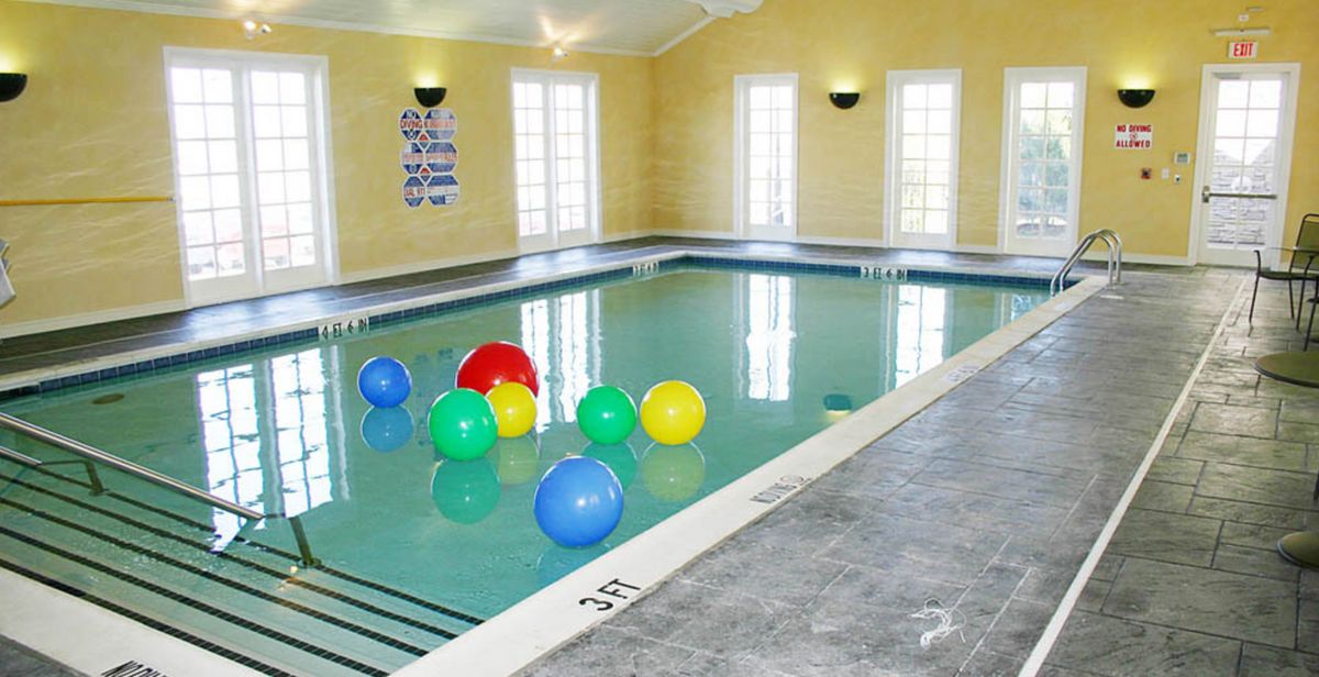 An indoor swimming pool with colorful beach balls floating on the water.