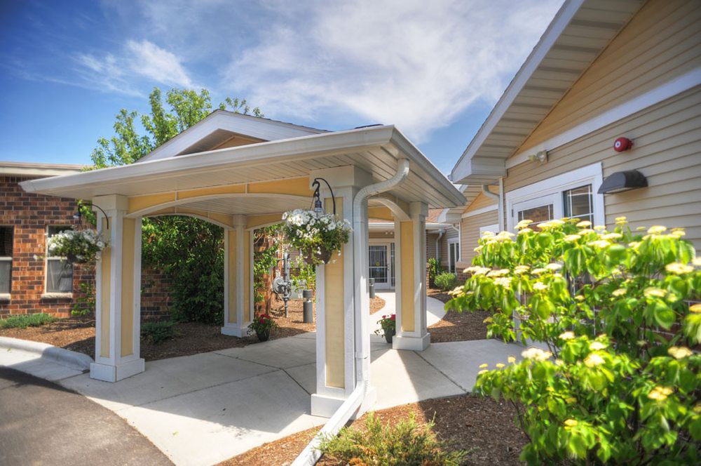 A beautifully designed house entrance with a garden and a canopy.