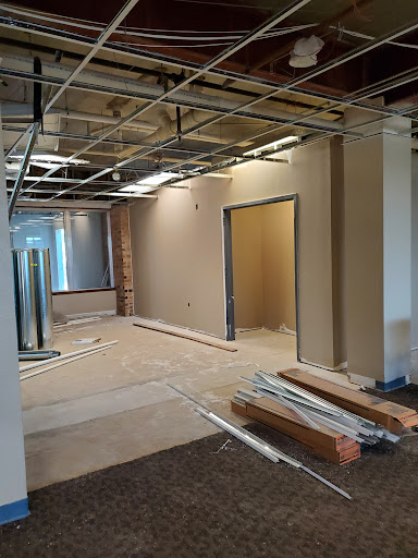 A view of an office space undergoing renovation, featuring exposed ceilings and walls ready for finishing.
