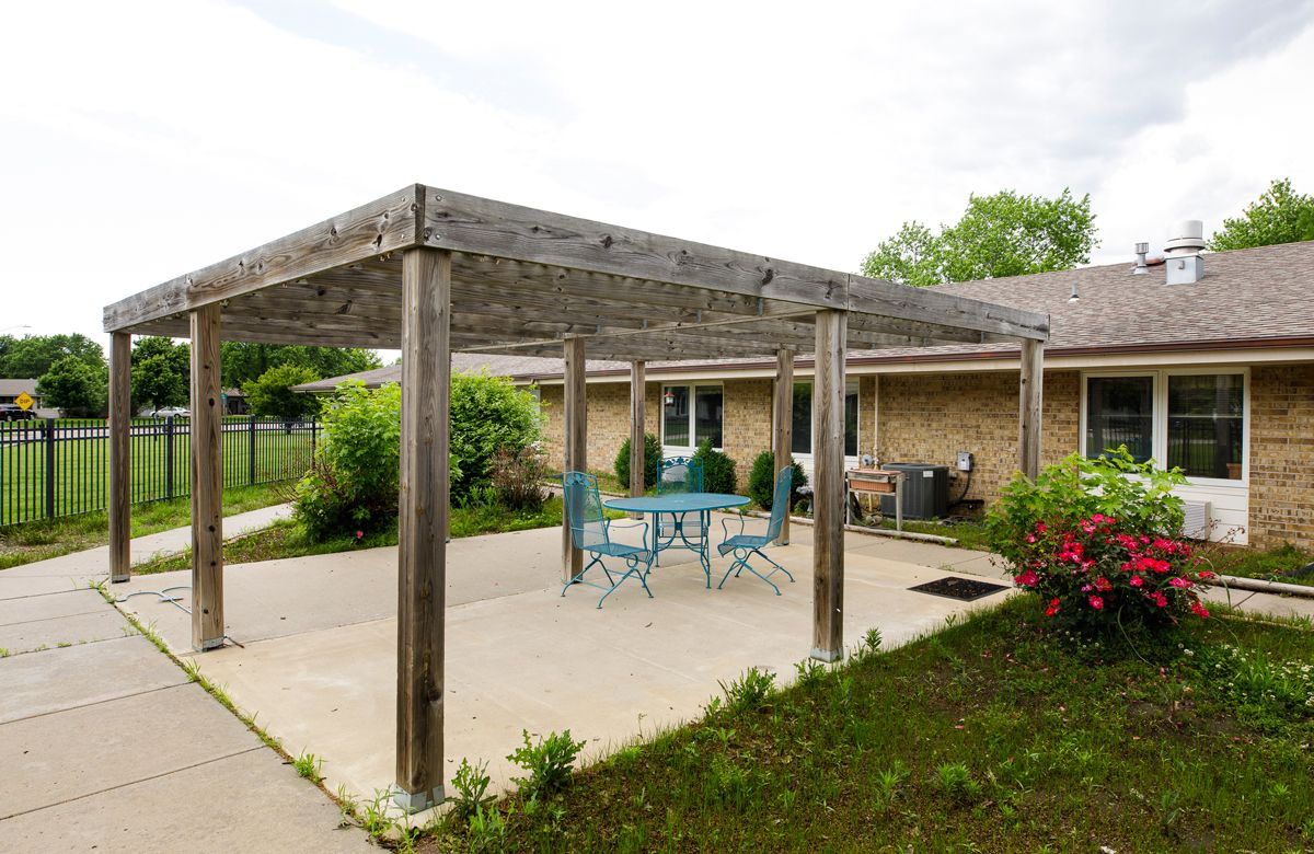 A backyard patio with a wooden pergola and outdoor seating.