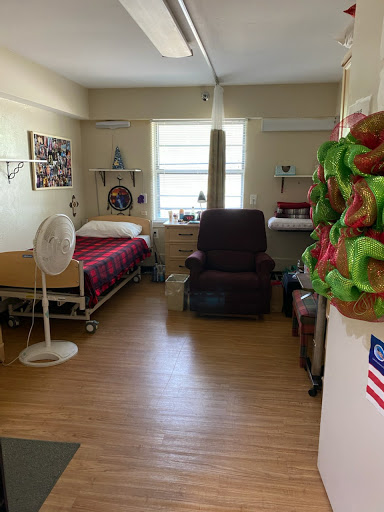A view of a patient's room in a hospital, featuring a bed, recliner chair, and personal touches.