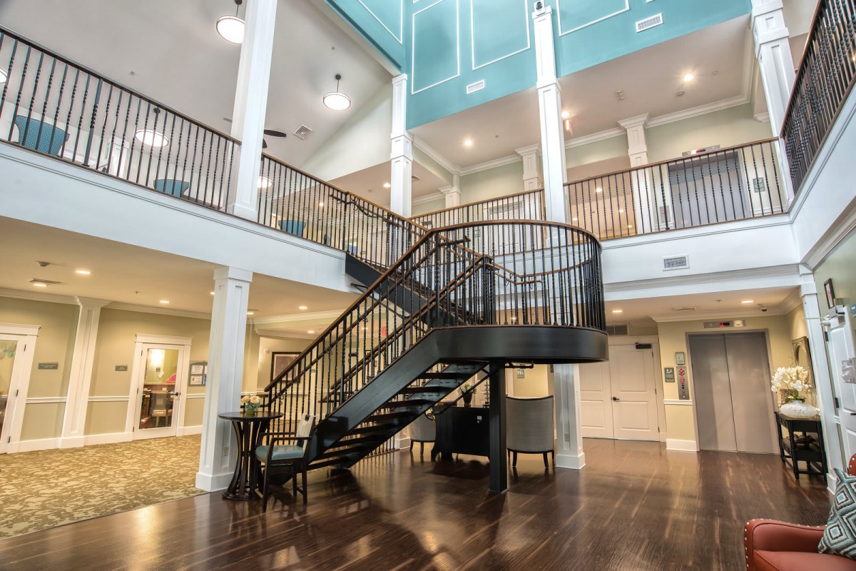 A modern interior featuring a grand staircase with wooden flooring and an open balcony design.