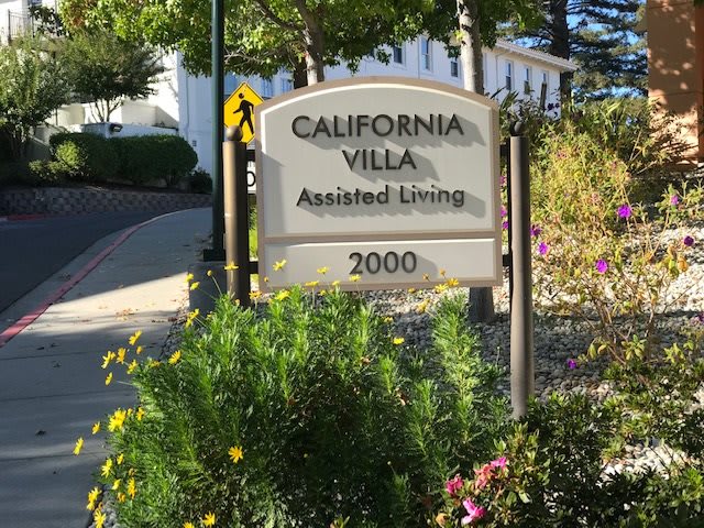 A sign for California Villa Assisted Living surrounded by greenery.