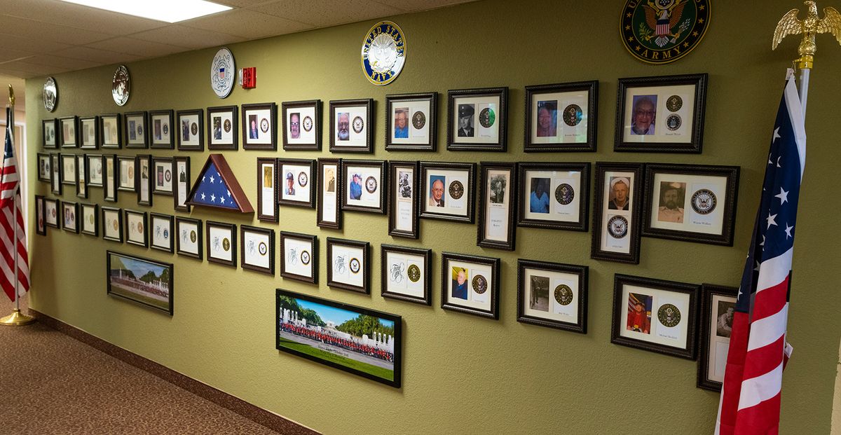 A wall showcasing various framed military photographs, awards, and memorabilia.
