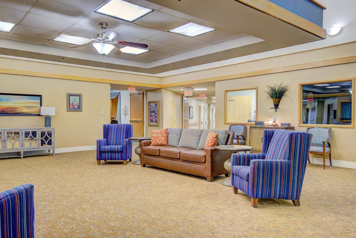 A cozy lobby area featuring a leather sofa, striped armchairs, and warm decor.