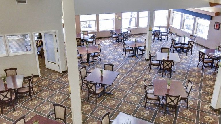 An empty dining room with several tables and chairs arranged neatly.