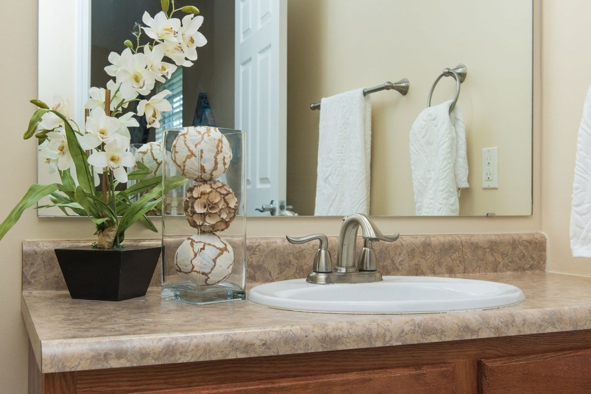 A neatly arranged bathroom countertop with decorative flowers and towels.