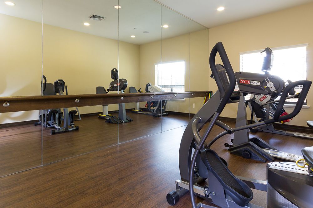 An indoor gym equipped with treadmills and other fitness equipment, featuring large mirrors on the wall.