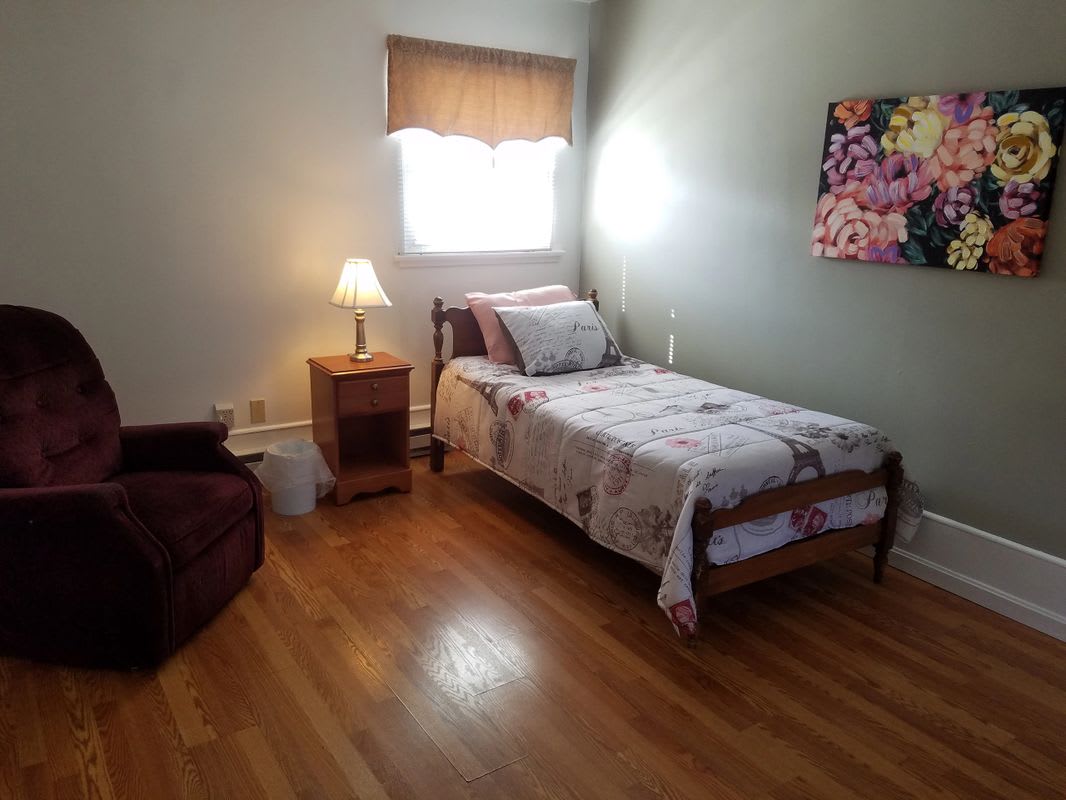A cozy bedroom with a single bed and wooden flooring.