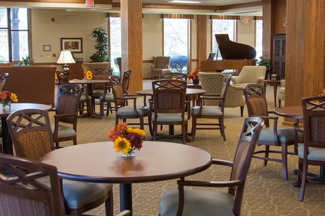 A cozy lounge area featuring tables, chairs, and a grand piano.