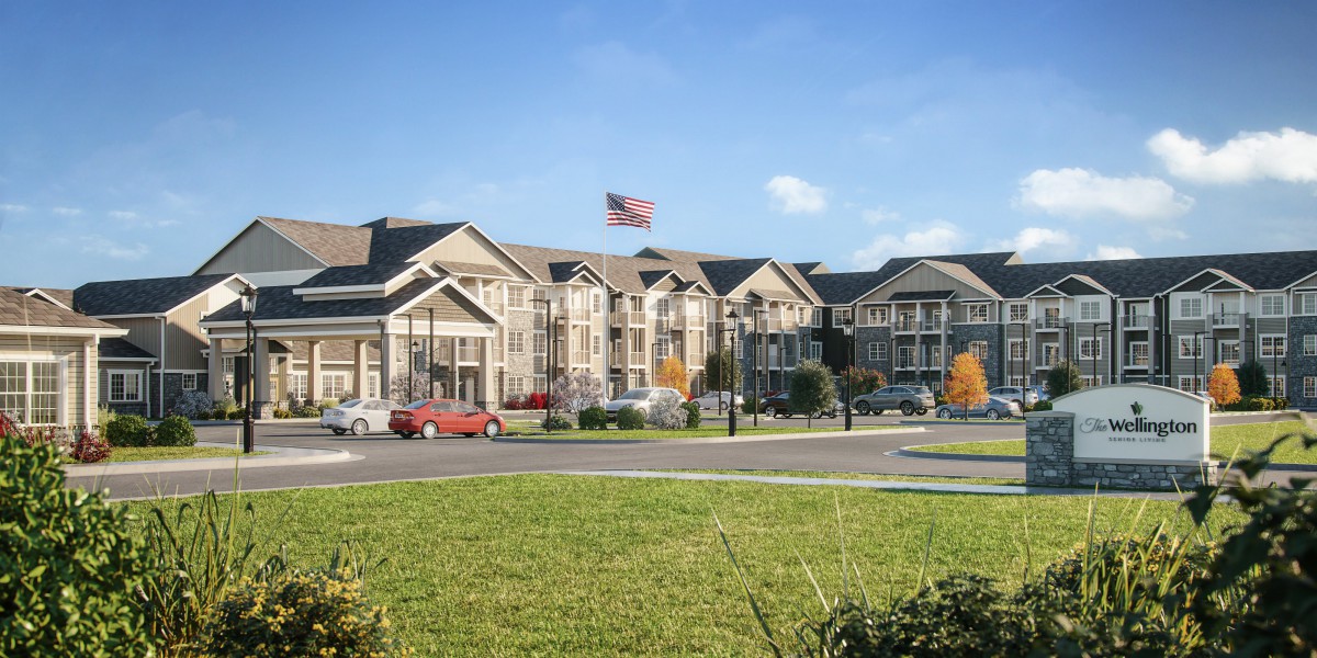 A residential building complex with well-maintained landscaping and an American flag displayed in front, under a clear blue sky.
