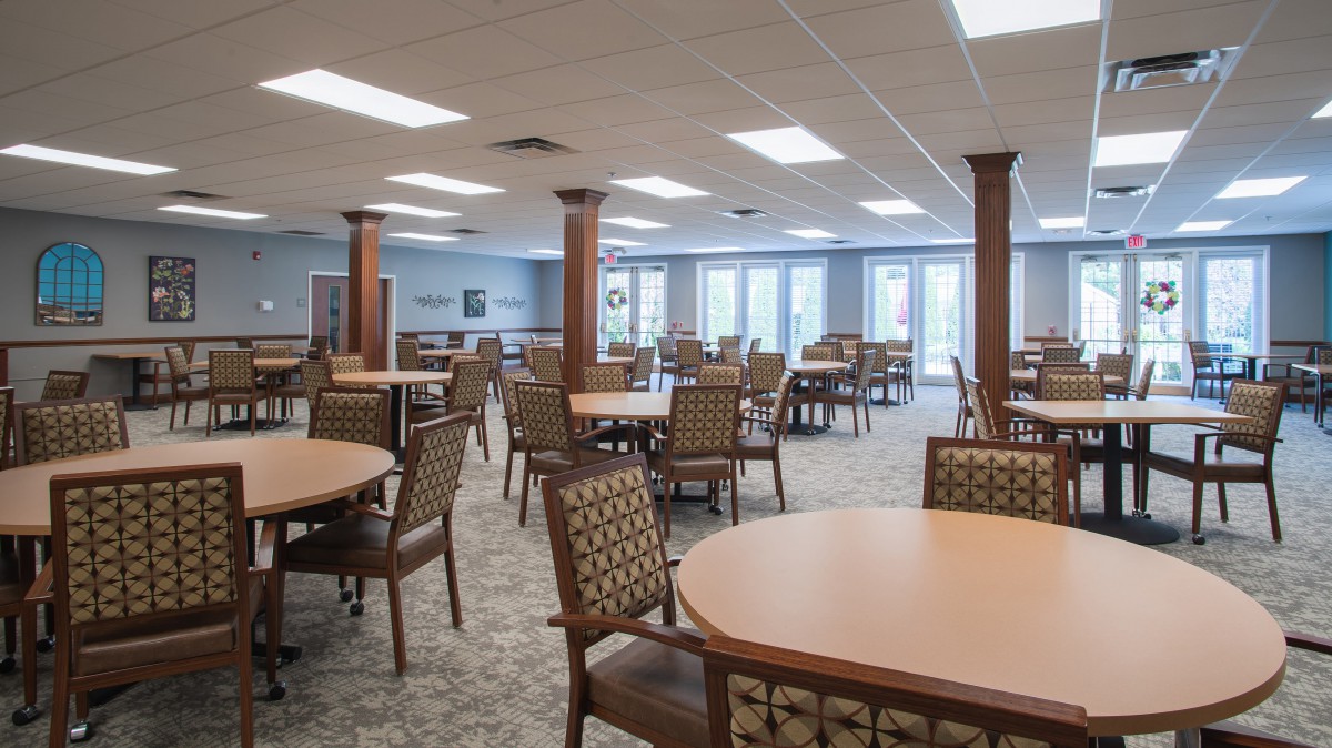 A spacious dining area with multiple tables and chairs arranged neatly under bright lighting.