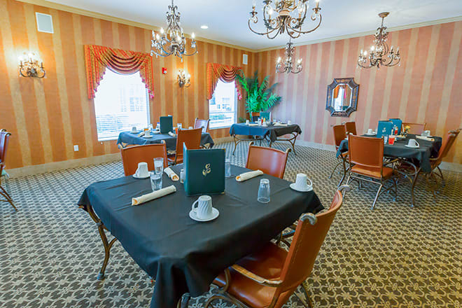 Elegant dining room with chandeliers and formal table settings.