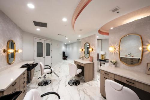 A modern beauty salon with elegant interior design, featuring stylish chairs and mirrors under sophisticated lighting.