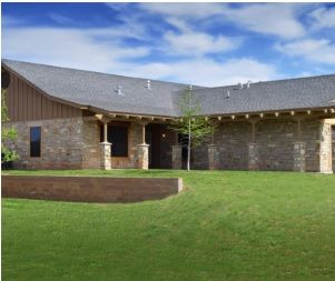 A modern house with a brick exterior and a spacious green yard under a clear blue sky.