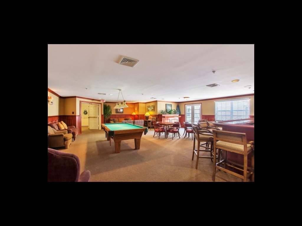 A cozy indoor space featuring a pool table and bar area with casual seating.