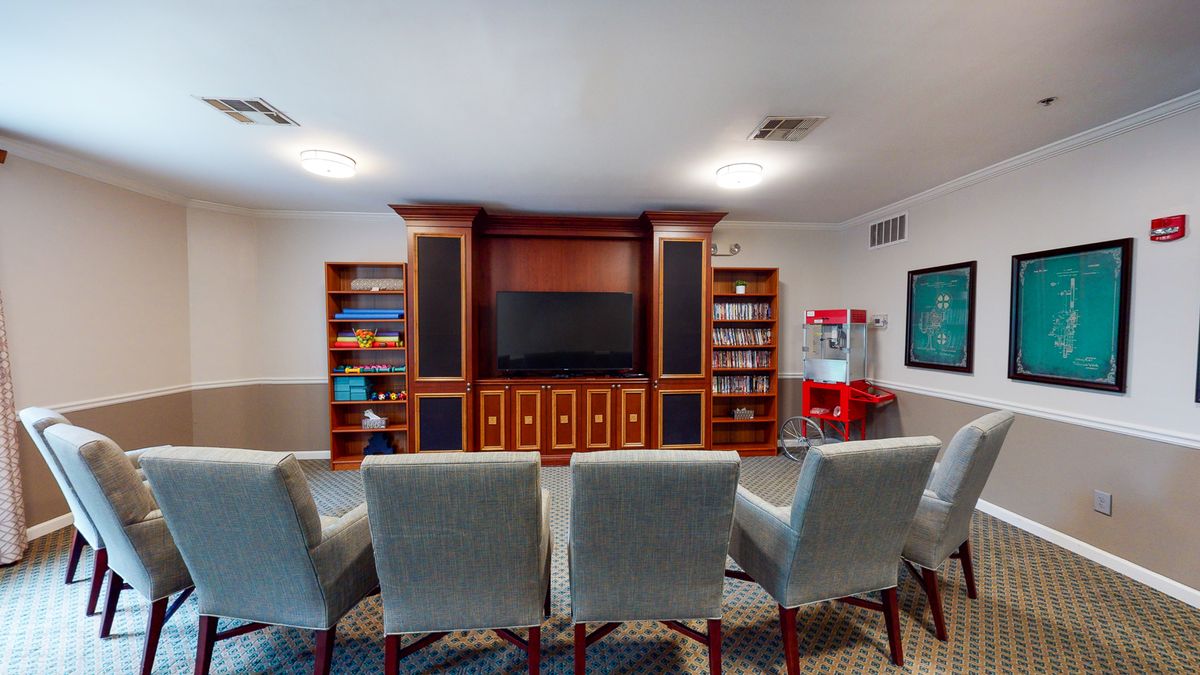 A cozy home theater with plush chairs, a large television, and built-in bookshelves.