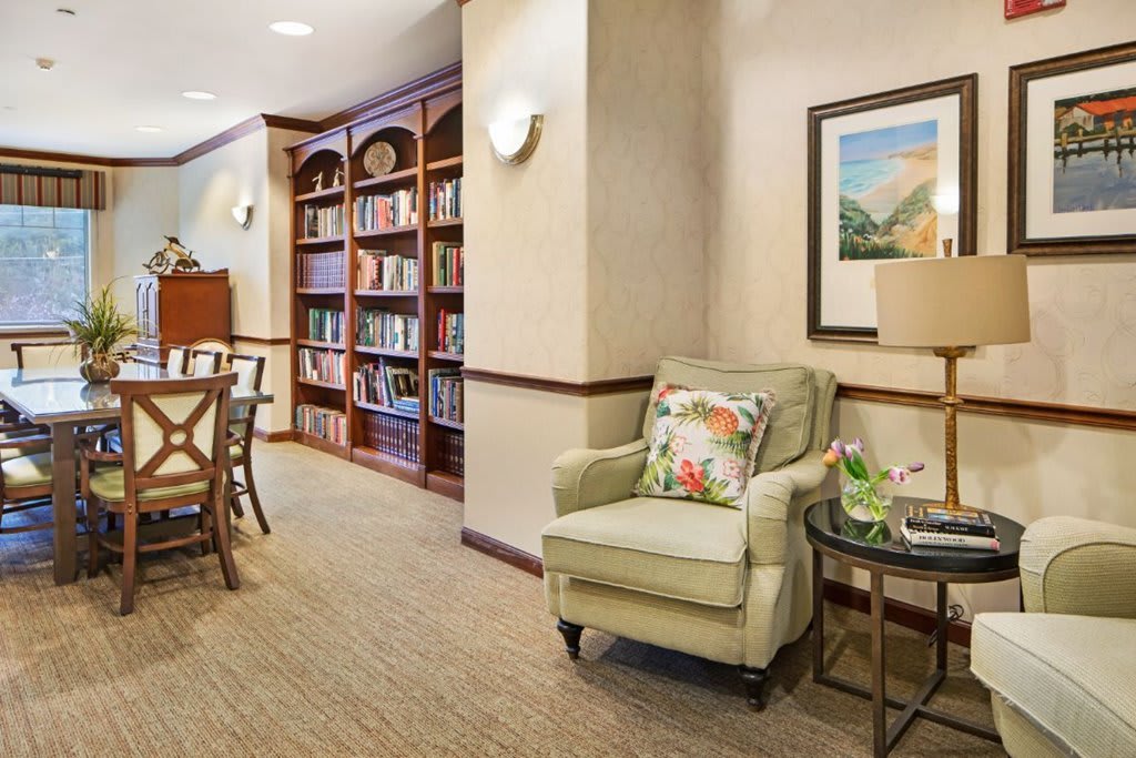 A cozy library reading area featuring a plush armchair, bookshelves, and warm decor.