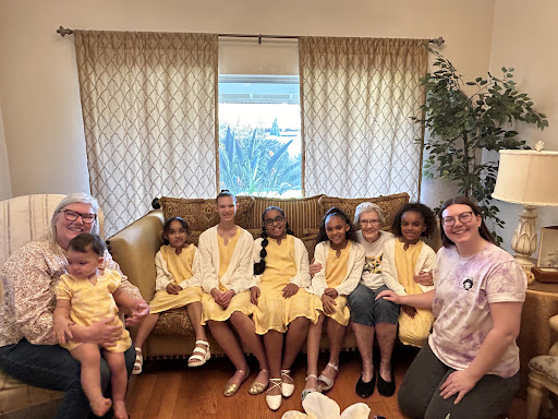 A joyful gathering of family members in matching yellow outfits, sharing smiles and laughter on a cozy sofa.