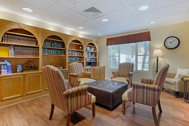 A cozy library reading room with striped armchairs and wooden bookshelves.
