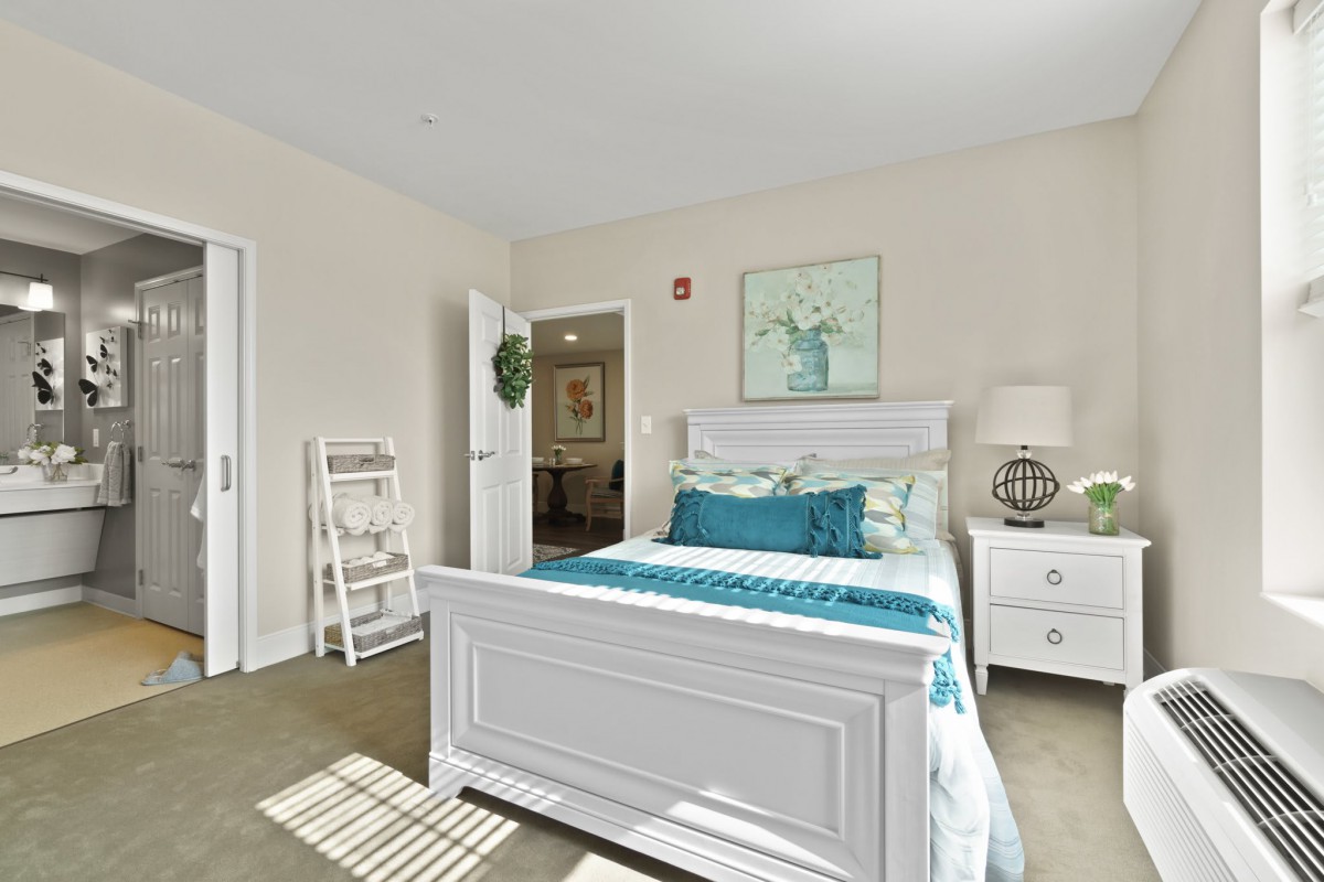 A well-lit, cozy bedroom with white furniture and teal accents.