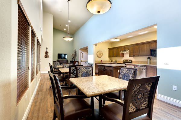 A spacious dining area with elegant tables and chairs, adjacent to a modern kitchen.