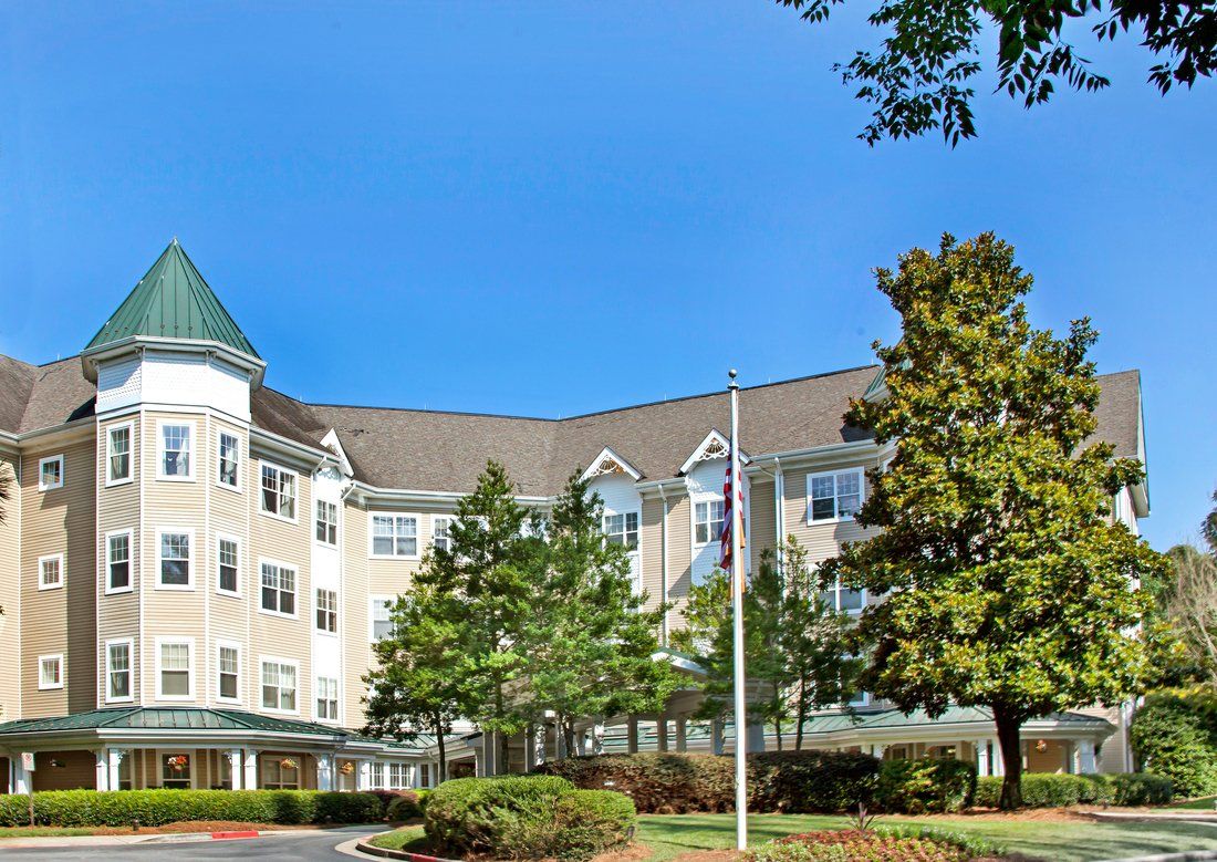 A multi-story building surrounded by trees with a clear blue sky in the background.