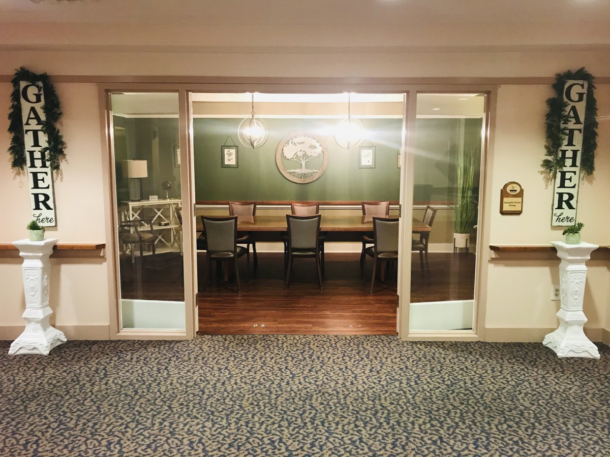 A conference room with a long table and chairs, visible through glass doors.
