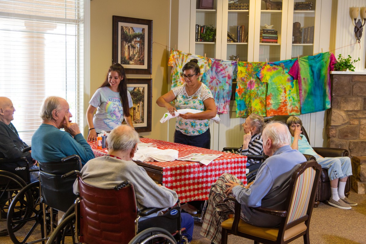A group of seniors engages in a tie-dye art activity indoors.