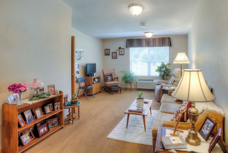 A cozy and well-lit living room with comfortable furniture, decorative elements, and a large window with curtains.