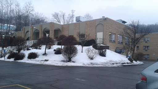 A cozy building surrounded by snow and winter foliage.