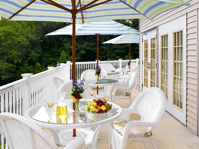 A sunny patio with tables and chairs under colorful umbrellas, perfect for relaxing.