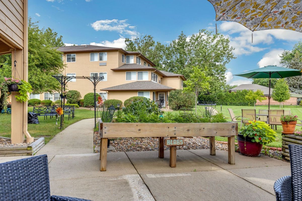 A spacious backyard featuring a raised vegetable garden and a multi-story house in the background.
