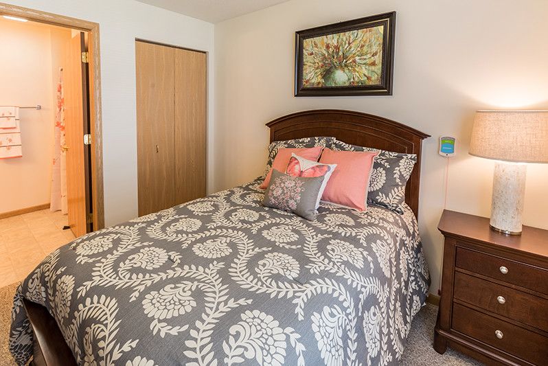 A cozy bedroom with a floral-patterned bedspread, decorative pillows, and framed artwork above the bed.