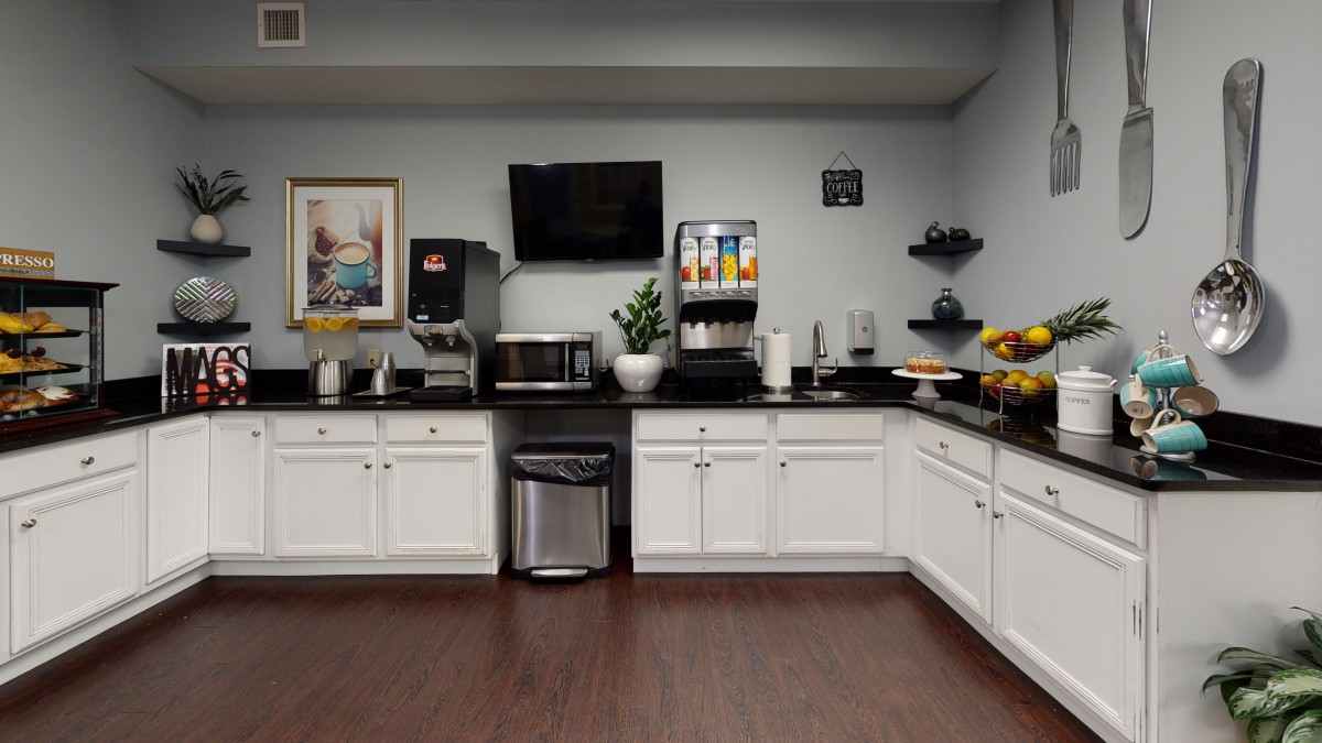 A modern kitchen breakfast area featuring a coffee station, beverage machines, and various snacks.